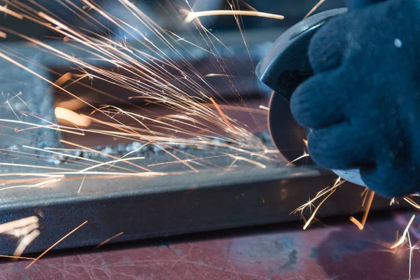 Metallo tagliato con una rettificatrice angolare. Sparks stanno volando. Strumento di costruzione smerigliatrice. Un uomo sta tagliando il metallo. Indossare guanti per la sicurezza . — Foto Stock