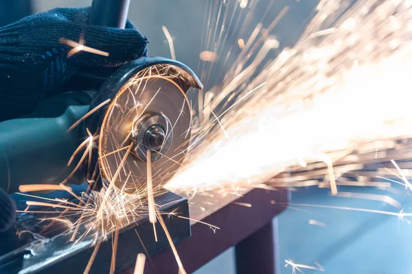 Metallo tagliato con una rettificatrice angolare. Sparks stanno volando. Strumento di costruzione smerigliatrice. Un uomo sta tagliando il metallo. Indossare guanti per la sicurezza . — Foto Stock