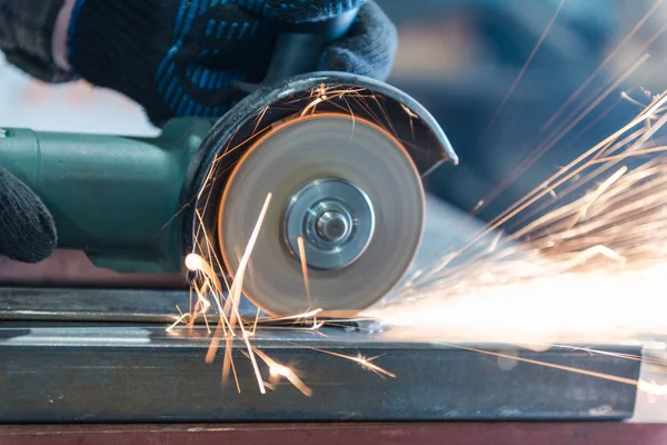 Metallo tagliato con una rettificatrice angolare. Sparks stanno volando. Strumento di costruzione smerigliatrice. Un uomo sta tagliando il metallo. Indossare guanti per la sicurezza . — Foto Stock