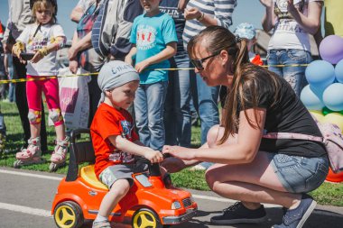 Zarinsk, Rusya-Haziran 3, 2017: küçük çocuklar bisiklete biniyor. Çocuklar mobiletlere ve çocuk arabalarına biniyor. Yazın sokakta çocuk tatili. Çocuklar gülümsüyor..