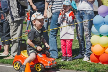 Zarinsk, Rusya-Haziran 3, 2017: küçük çocuklar bisiklete biniyor. Çocuklar mobiletlere ve çocuk arabalarına biniyor. Yazın sokakta çocuk tatili. Çocuklar gülümsüyor..