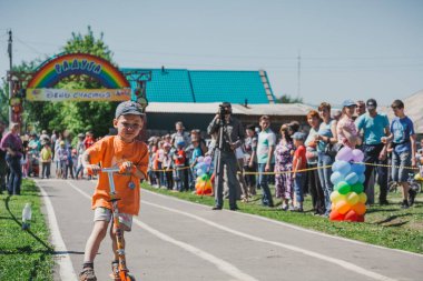 Zarinsk, Rusya-Haziran 3, 2017: küçük çocuklar bisiklete biniyor. Çocuklar mobiletlere ve çocuk arabalarına biniyor. Yazın sokakta çocuk tatili. Çocuklar gülümsüyor..