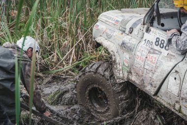 Zarinsk, Rusya-16 Ağustos 2017: arabalar çamurun içinden geçiyor. Arabalar bataklıktan ve ormandan geçer. Erkekler arabaları itiyor. Arabalarda yarışmalar.