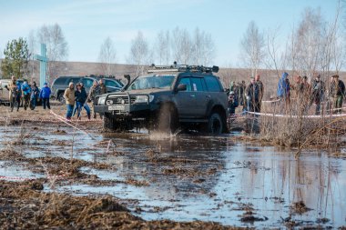 Zarinsk, Rusya -15 Nisan 2017: arabalar baharda çamurun içinden geçer. Arabalar bataklıktan geçer. Erkekler arabaları itiyor. Arabalarda yarışmalar.