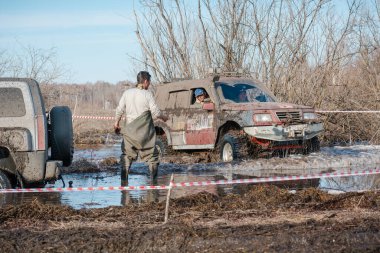 Zarinsk, Rusya -15 Nisan 2017: arabalar baharda çamurun içinden geçer. Arabalar bataklıktan geçer. Erkekler arabaları itiyor. Arabalarda yarışmalar.