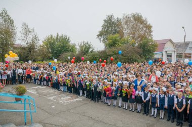 Zarinsk, Rusya-Eylül 01, 2017, bilgi günü, 1 Eylül, öğrenciler okulun önünde elinde çiçeklerle dikiliyor, çocuklar tüm sınıf tarafından bir hükümdarın üzerine inşa ediliyor. Okul üniformalı öğrenciler..
