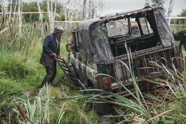 Zarinsk, Rusya-16 Ağustos 2017: arabalar çamurun içinden geçiyor. Arabalar bataklıktan ve ormandan geçer. Erkekler arabaları itiyor. Arabalarda yarışmalar.