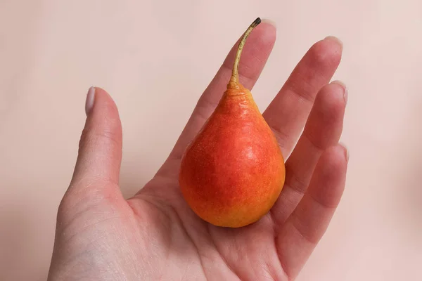 Vrouw hand houden van een peer op pastel achtergrond — Stockfoto