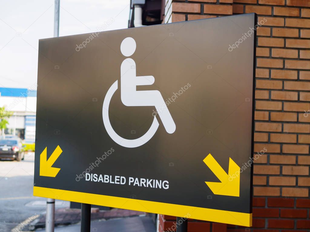 Disabled parking space sign and symbols on a pole warning motorists