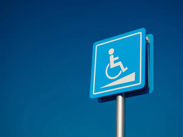 Espacio de estacionamiento para discapacitados y señal de manera silla de ruedas y símbolos en un poste de advertencia a los automovilistas —  Fotos de Stock