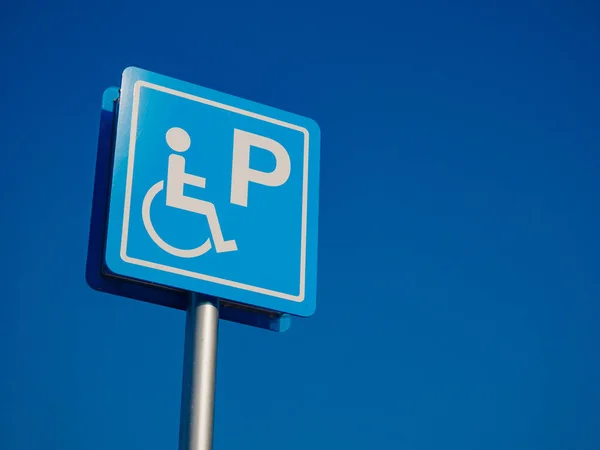 Espacio de estacionamiento para discapacitados y señal de manera silla de ruedas y símbolos en un poste de advertencia a los automovilistas — Foto de Stock