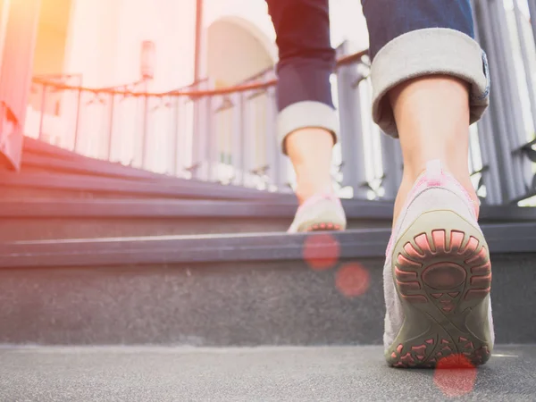 Pretty woman is stepping up a staircase with Lens Flare or sunspot — Stock Photo, Image