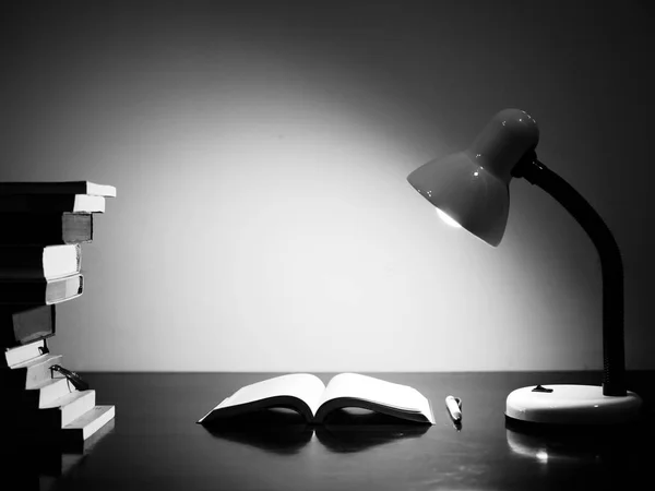 Black and white of Stack Books on wooden table under lamp light — Stock Photo, Image