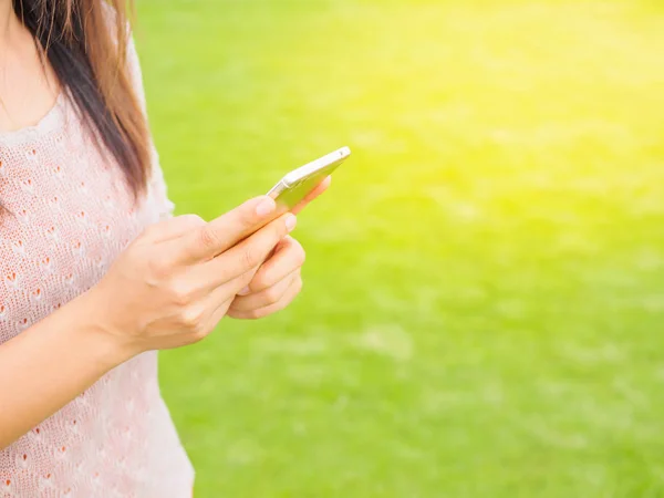 Pretty Young woman using smart phone. Female working on cell phone on green grass field