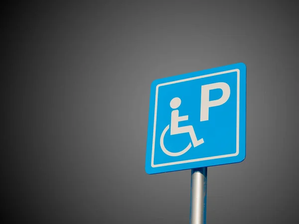 Espacio de estacionamiento para discapacitados y señal de acceso para silla de ruedas y símbolos en un poste que advierte a los automovilistas que se aíslen en el degradado Fondo blanco y negro — Foto de Stock