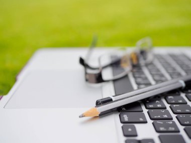 Dizüstü bilgisayar, dizüstü bilgisayar, gresses ve yeşil çimenlerin üzerinde kalem