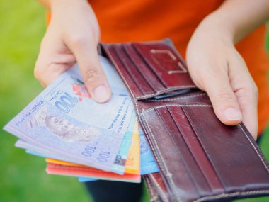 Kadınların elleri yeşil çim sahada cüzdanından para Malezya Ringiti yaptırmayı