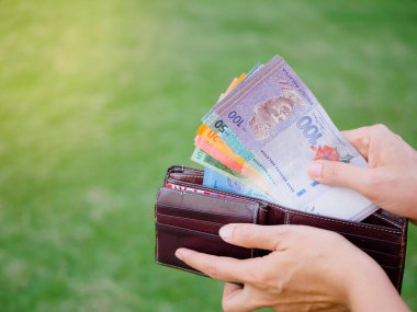 Kadınların elleri yeşil çim sahada cüzdanından para Malezya Ringiti yaptırmayı