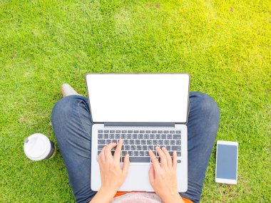 Dizüstü bilgisayar kullanan genç ve güzel kadın. Bir açık yeşil çim sahası içinde laptop üzerinde erkek