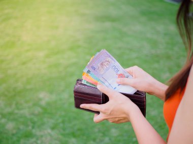 Kadınların elleri yeşil çim sahada cüzdanından para yaptırmayı