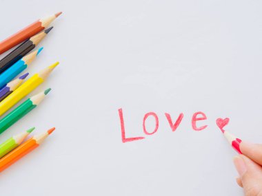 Sevgi ve kırmızı kalpli beyaz kağıda renkli kalemler