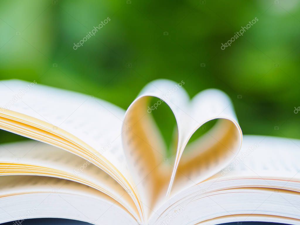 book on table in garden with top one opened and pages forming heart shape