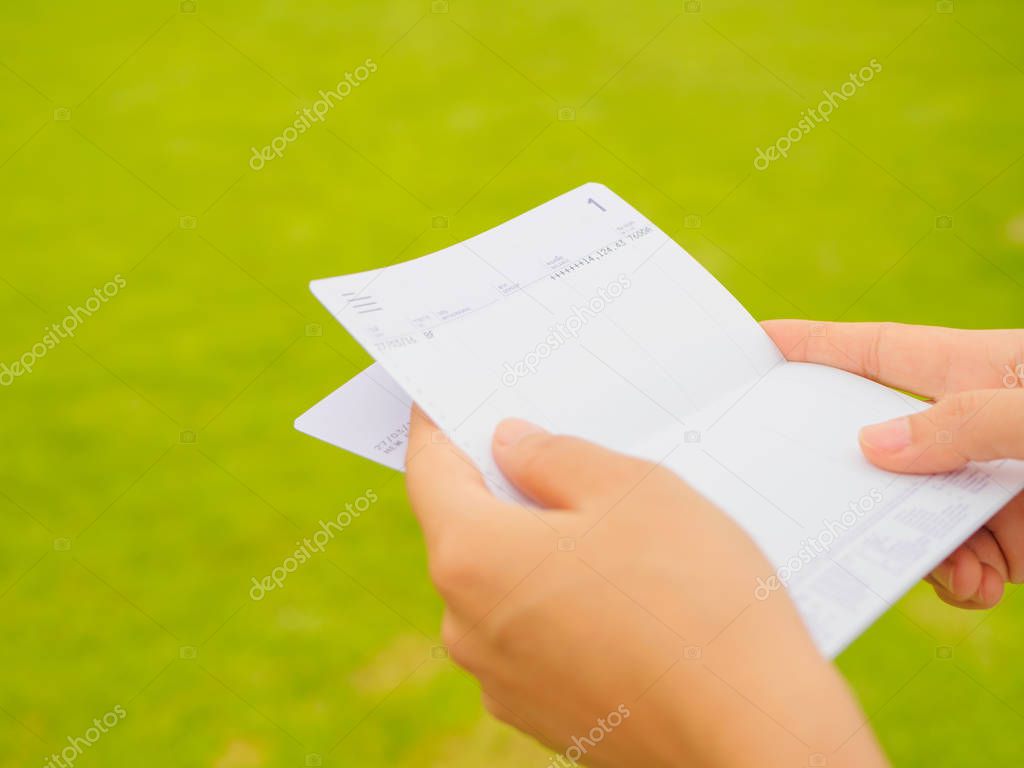 hands holding saving account passbook, book bank on the green grass background