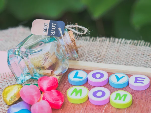 Love Mom buchstabiert mit bunten Buchstabenblöcken und einem roten Herz isoliert auf Holzbrett und Sack - Muttertag — Stockfoto