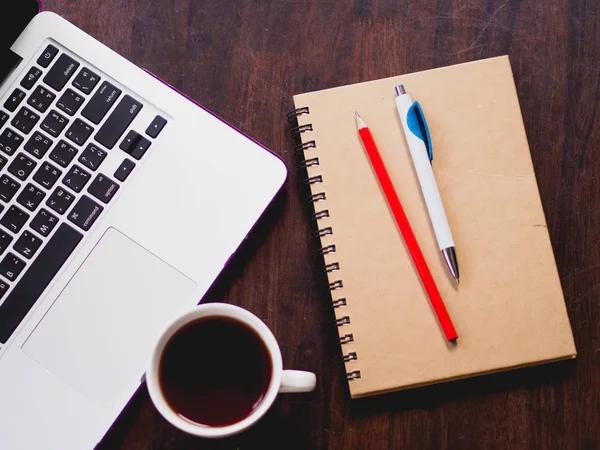 Bovenaanzicht van werkplek met laptop koffie en boek op houten bureau. — Stockfoto