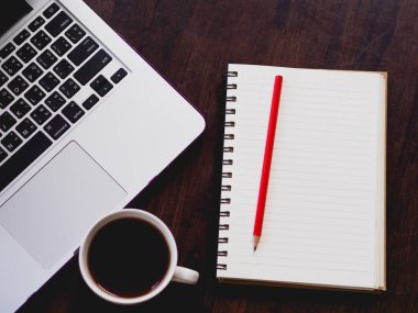 çalışma alanı'nın üst görünümüyle dizüstü kahve ve ahşap masa üzerinde kitap.
