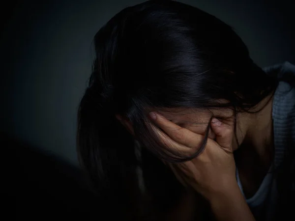 Mujer triste abrazar su rodilla y llorar. Mujer triste sentada sola en una habitación vacía . — Foto de Stock