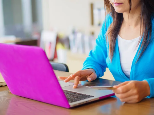 Csinos, fiatal womans keze gazdaság egy hitelkártya, és segítségével a laptop számítógép részére online bevásárlás — Stock Fotó