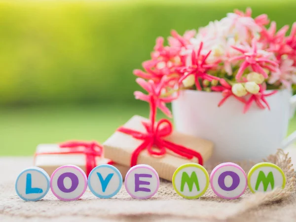 Концепція дня матері. LOVE MOM алфавіт з подарунком і квіткою на фоні — стокове фото