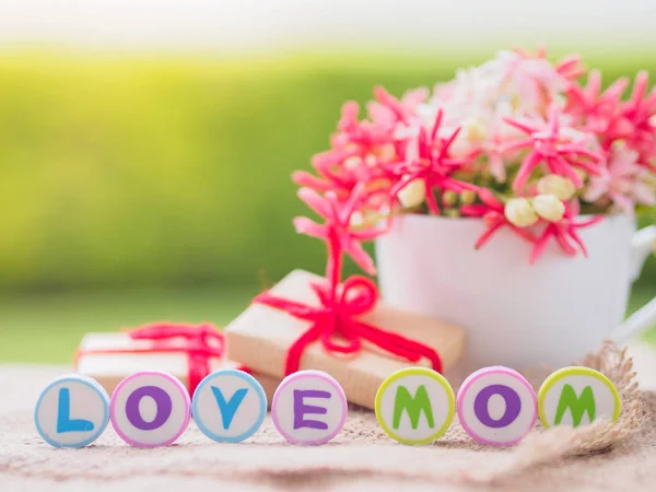 Muttertagskonzept. Liebe Mama Alphabet mit Geschenk und Blume auf dem Hintergrund — Stockfoto