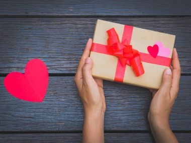 bir hediye kutusu ahşap masa üzerinde tutan eller. Tasarımınız için Festival arka plan.