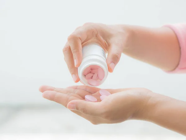 A young woman pours out medicine into her hand — Stock Photo, Image