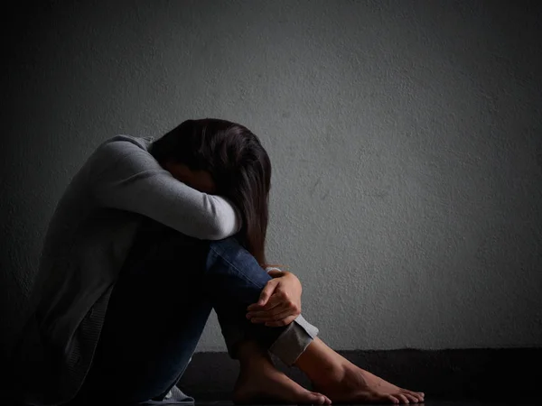 Sorgliga kvinnan krama henne knä och gråta. Sorgliga kvinna sitter ensam i ett tomt rum. — Stockfoto
