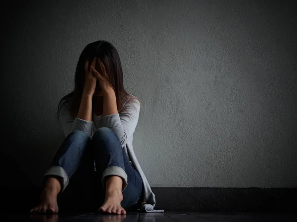 Szomorú nő ölelés a térd, és sírni. Szomorú nő egyedül ül egy üres szobában. — Stock Fotó