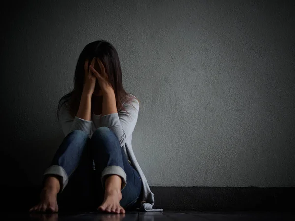 Mujer triste abrazar su rodilla y llorar. Mujer triste sentada sola en una habitación vacía . — Foto de Stock