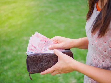 Kadınların elleri yeşil çim sahada cüzdanından para Tayland Bahtı yaptırmayı