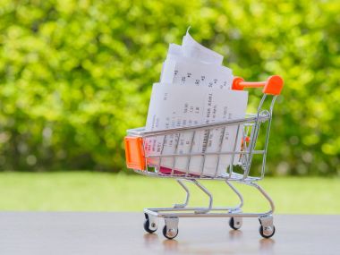 Alışveriş sepeti ahşap masa üzerinde receiptwith paralar, bakkal giderleri ve tüketicilik için kavramı ile