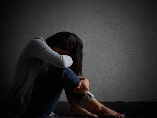 Mulher triste abraçar o joelho e chorar. Mulher triste sentada sozinha em um quarto vazio . — Fotografia de Stock