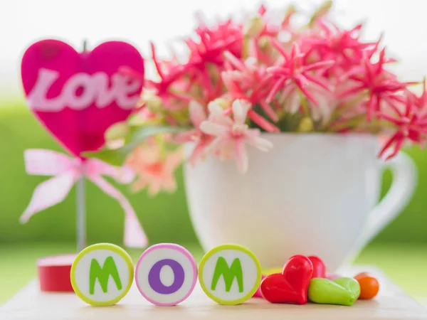 Concepto del día de la madre. LOVE MOM alfabeto con corazón colorido y flor en el fondo —  Fotos de Stock