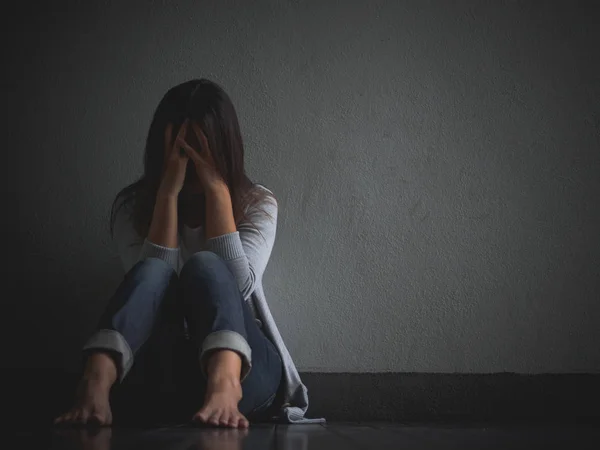 Mujer triste abrazar su rodilla y llorar. Mujer triste sentada sola en una habitación vacía . —  Fotos de Stock