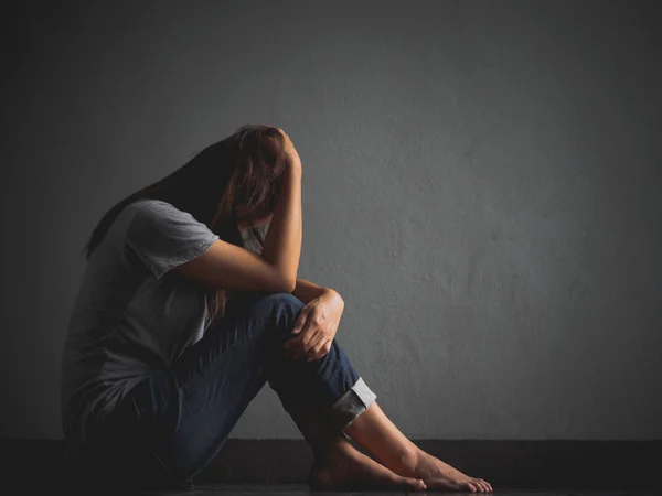 Mujer triste abrazar su rodilla y llorar. Mujer triste sentada sola en una habitación vacía . — Foto de Stock