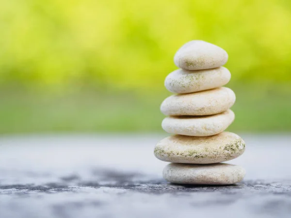 Balance Stones stacked to pyramid in the soft green background to Spa ideas design or freedom and stability concept on rocks.