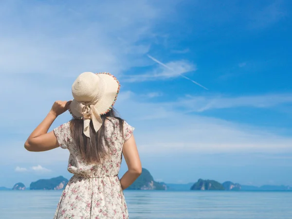 Mujer en vacaciones de verano con sombrero de paja y vestido de playa disfrutando de la vista al mar — Foto de Stock