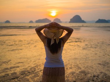 Kadın şapkası güneşin altında Kollarını açarak denize yakın