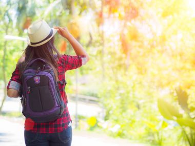Yol ve orman arka planda mutlu Asyalı kız sırt çantası, 