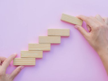Başarı temel yapı kavramı. Kadın el bulmaca tahta bloklar bir merdiven şeklinde koymak